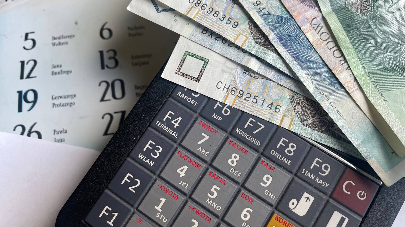 Polish zloty banknotes lying on a calculator with a calendar behind them.
