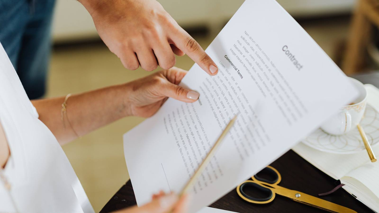 Two people going over a contract together at an office desk.