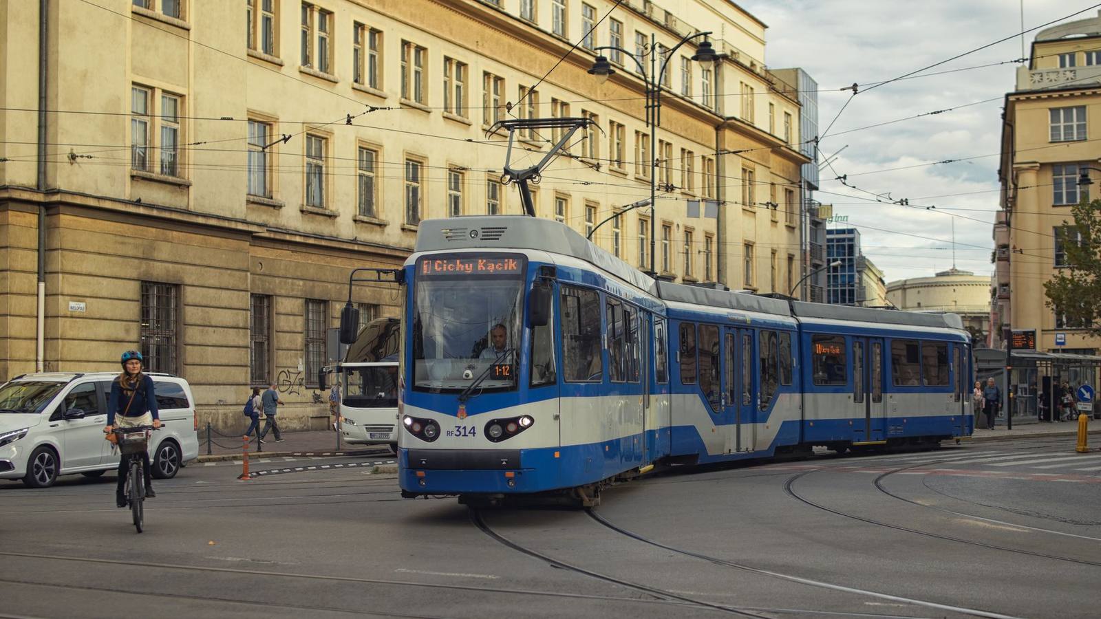 A blue tram running along a street lined with buildings in Krakow.