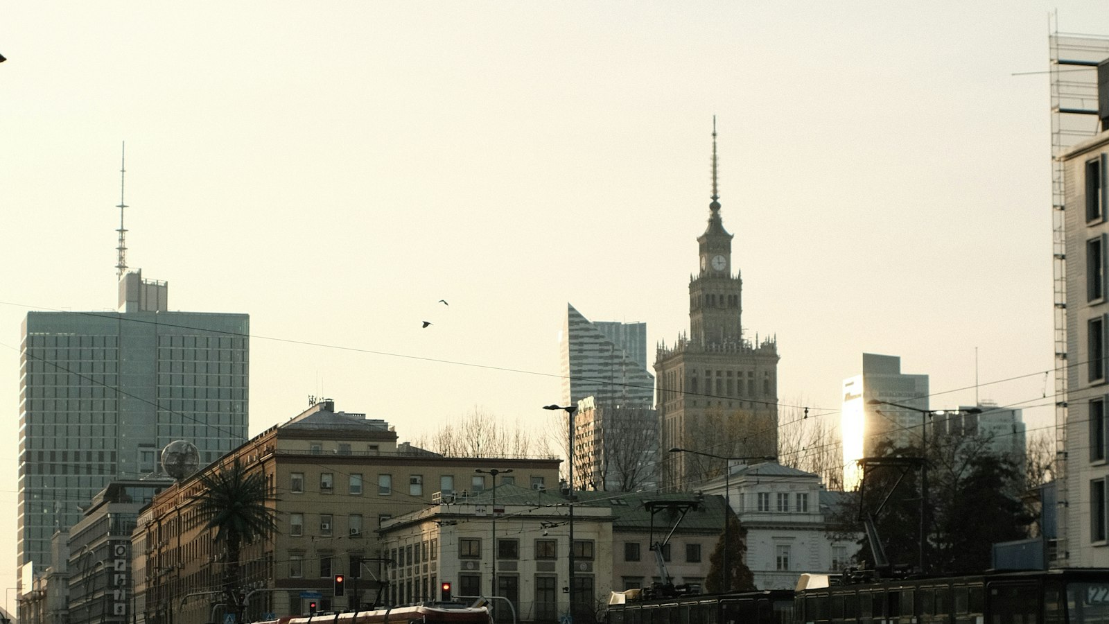 Warsaw's skyline with the Palace of Culture and Science, seen behind a passing tram at dusk