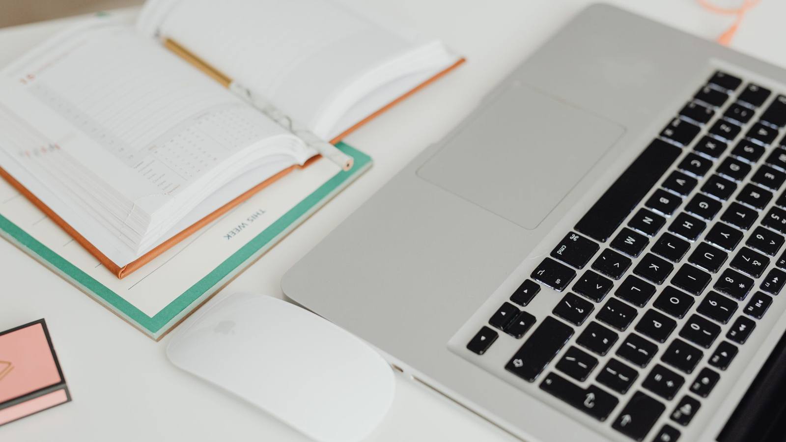 An open planner and a laptop on a tidy desk, seen from above.