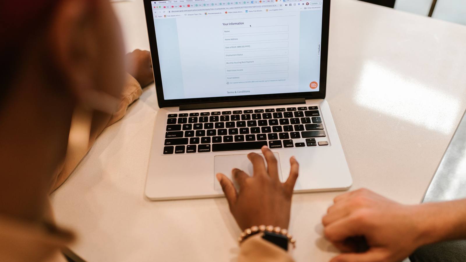 Two people filling out an online form on a laptop.