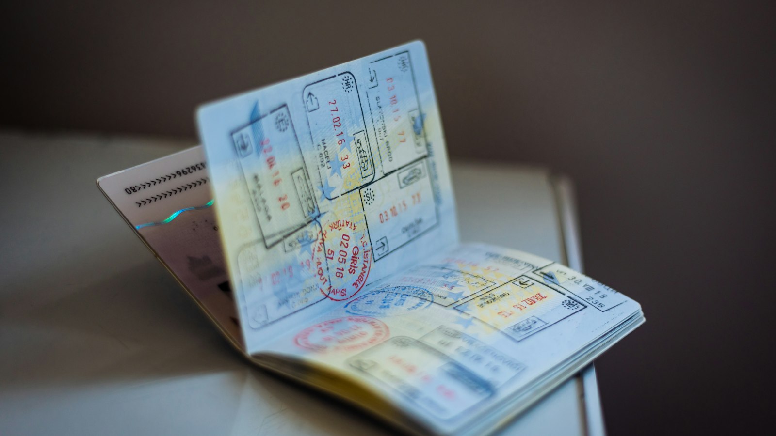 An open passport with numerous ink stamps resting on a table